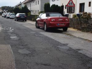 Ein Foto (Mathilde Thiel), das den schlechten Zustand der Straße zeigt.