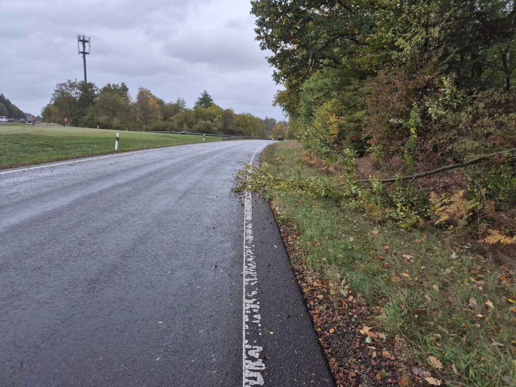 Landstraße mit einem Ast am Fahrbahnrand nach Sturm