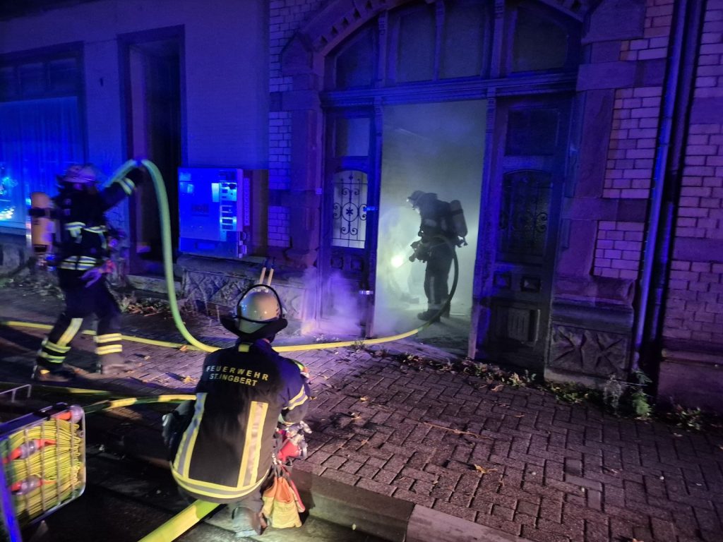 Feuerwehrleute unter Atemschutz an einer verrauchten Haustür in der Kohlenstraße