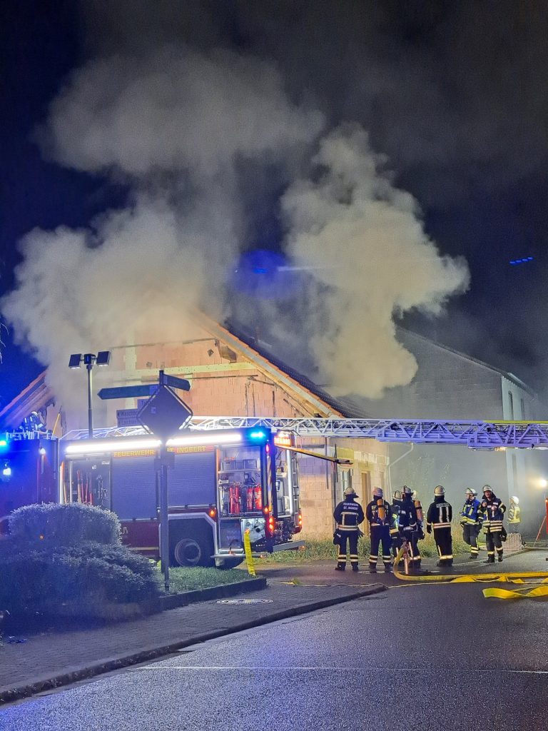 Rauch über einem Wohnhaus in der Hauptstraße in Oberwürzbach, davor Feuerwehrfahrzeuge und Einsatzkräfte