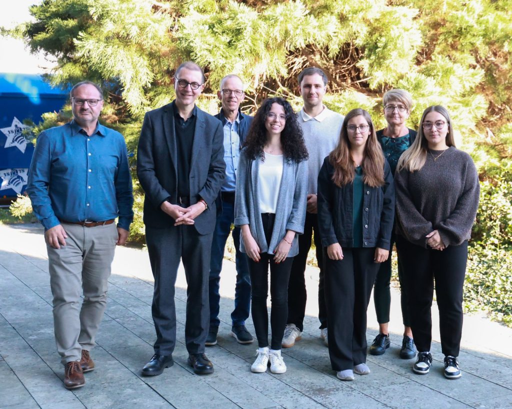Gruppenfoto der neuen Anwärter mit Oberbürgermeister und Verwaltungsmitarbeitern vor einer Hecke
