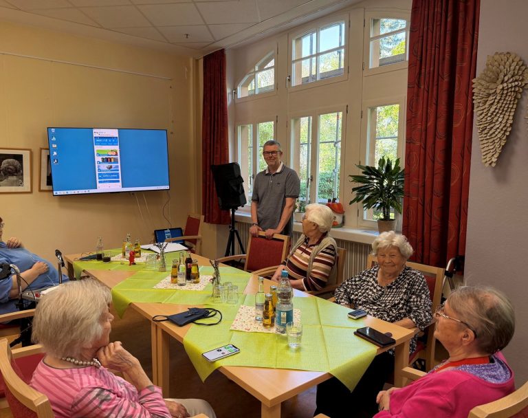 VHS-Dozent Ulrich Struth erklärt Seniorinnen im Fidelishaus die Stadtapp am Bildschirm